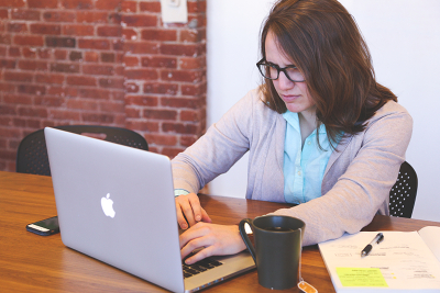 Stock art taken from Pexels of a woman stressing over a MacBook.